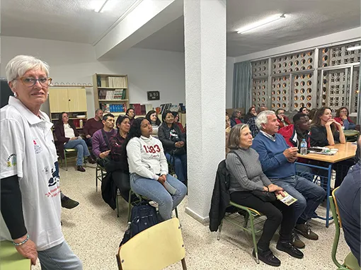 Personas de diferentes edades y culturas, sentadas en un aula escuchando una charla informativa de la asociación William Martin.