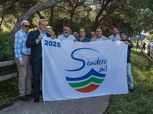 Componentes de la asociación William Martin, sujetando una bandera de sendero azul en Punta Umbría, Huelva.